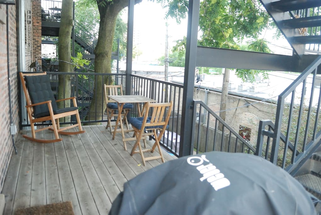 Deck with gas grill. The lights of Wrigley Field are visible in the distance when the Cubs are playing.
