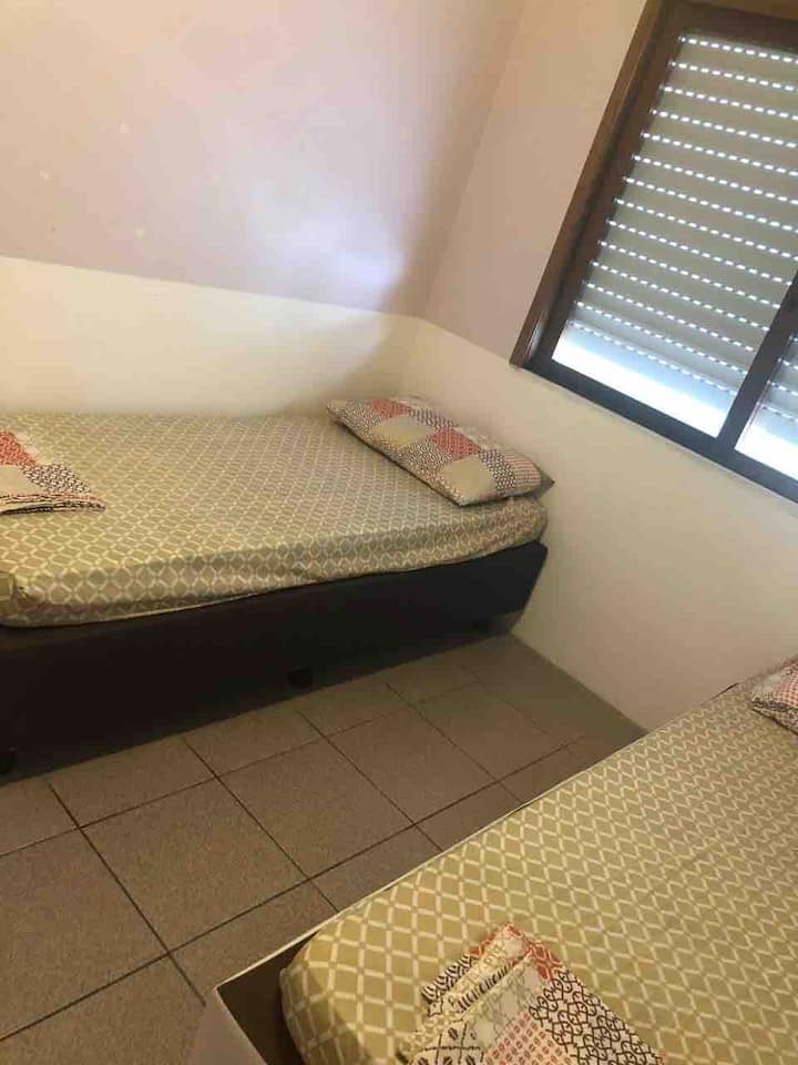 Общежитие с две единични легла и вентилатор на тавана. 