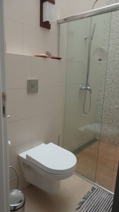 banheiro com iluminação natural, vaso sanitário suspenso e aquecimento solar