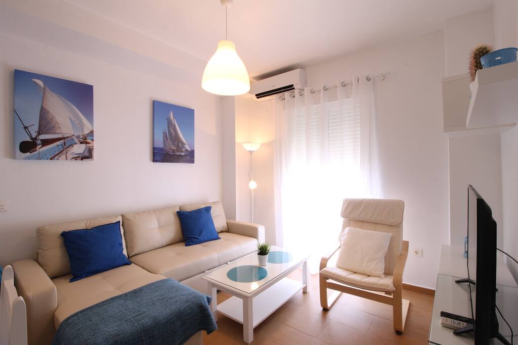 Salón con sofá cama grande, tipo Cheslong, y aire acondicionado.