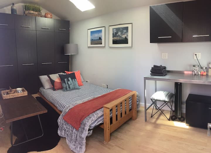Inspirado en Cannon Beach, Oregón, nuestro moderno bungalow ubicado en nuestro patio trasero, sirve como nuestro cuarto dormitorio.  Relájate mientras la luz natural se vierte en un cómodo colchón matrimonial.  El espacio tiene calefacción y aire acondicionado, así como una mininevera y una mininevera. 