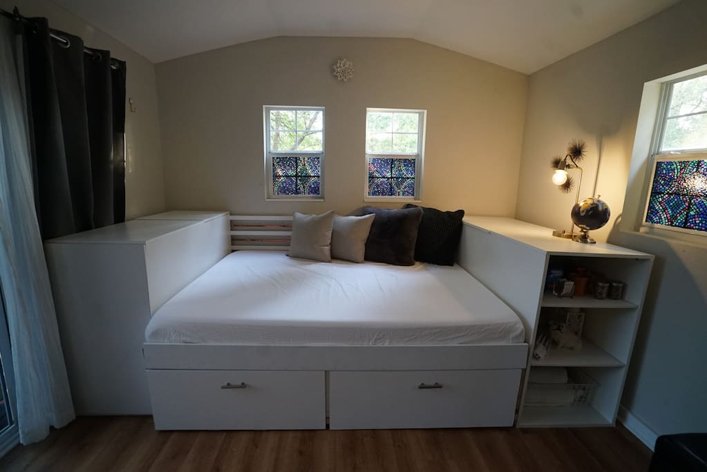 The lockable detached studio hosts a memory foam queen-sized day bed, with custom storage for guests staying for longer time spans.
A large desk & office chair make for the ideal workspace.
Hosts a mini-fridge (with ample fridge and freezer space) and coffee maker, and it's own AC unit.
The glass doors are tinted to reduce sunlight, and the little windows have wooden shades that can provide more privacy.
Guests will use the in-home bathroom and kitchen.
