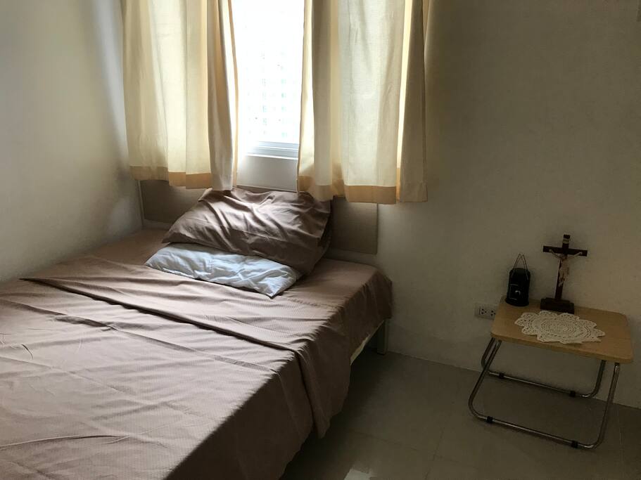 Double sized bed with 2 pillows. Bed side table and small lamp shade.