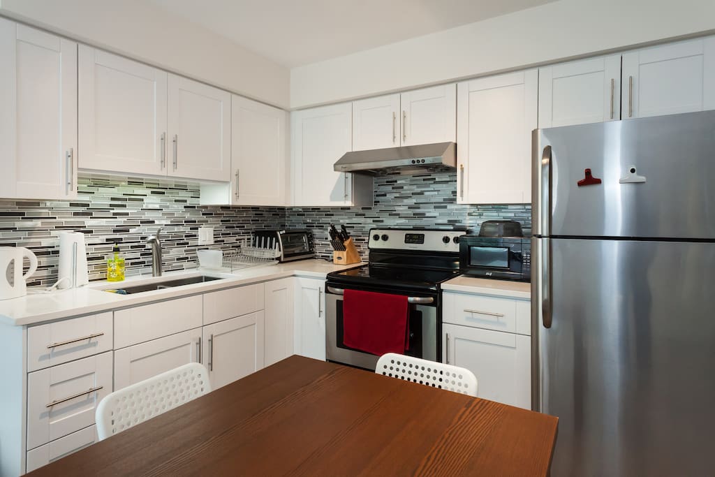 New and fully equipped kitchen with stainless steel appliances, quartz counter top, and tiled back splash.
