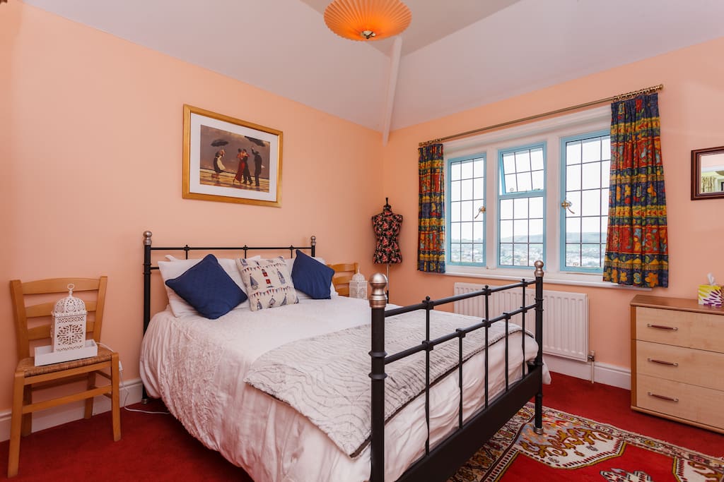 This shows the room as entered. There are bedside cabinets now and a wardrobe on the left side, out of view here plus a mirror on the wall above a fireplace opposite the bed.