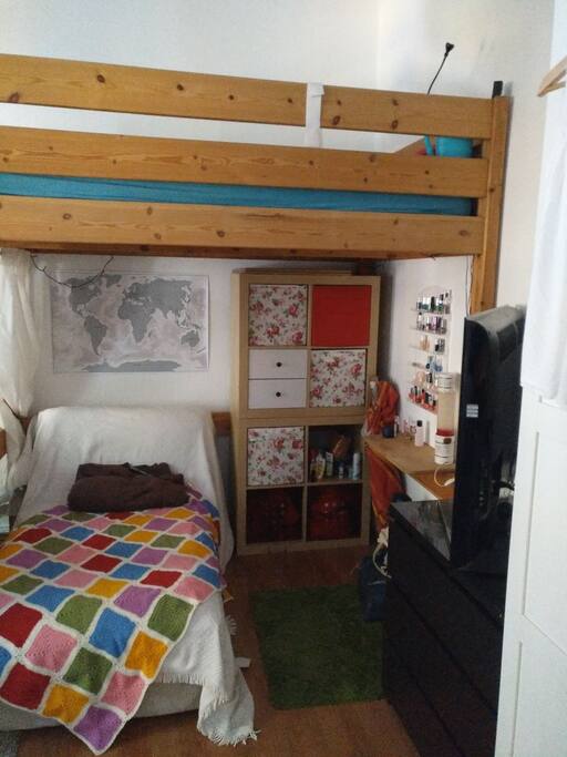 A sofa and tv are under the loft bed