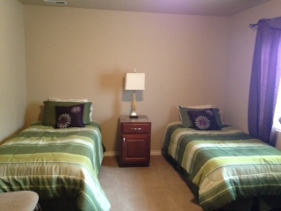 Second bedroom with two twin beds and a treadmill and a spacious closet.