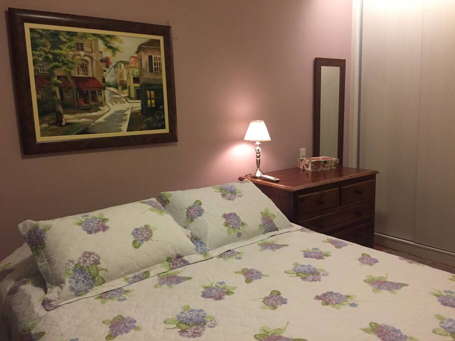 Suíte: cama queen e armário planejado no fundo.
