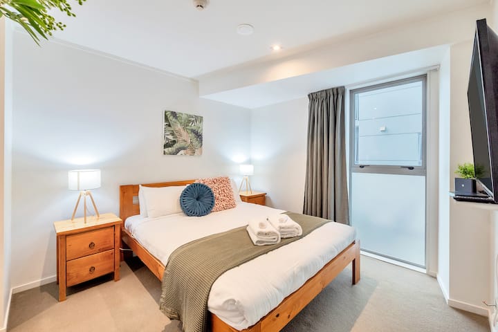 ห้องนอนชั้นบนมีเตียงขนาดควีนไซส์โต๊ะข้างเตียง 2 ตัวและโคมไฟทันสมัย 