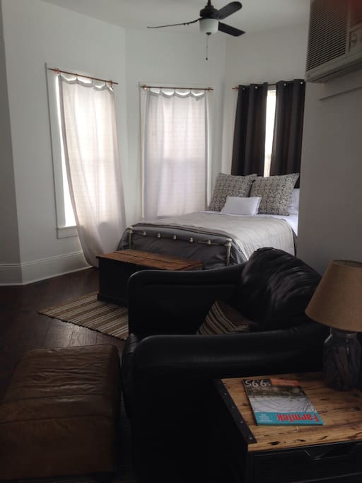 Full bed in a window nook and oversized leather chair and ottoman.