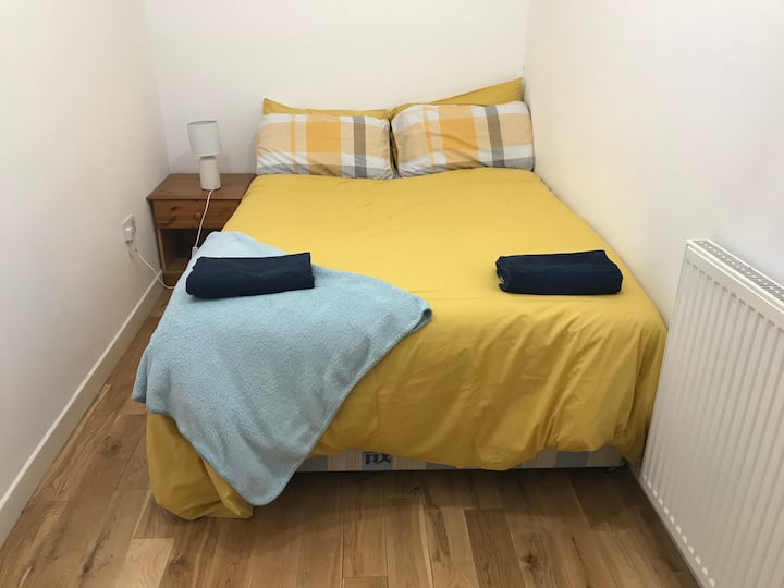 בחדר שינה 2 יש גם מיטה זוגית גדולה, שולחן ליד המיטה, מנורה, טלוויזיה וארון מגירות גדול.