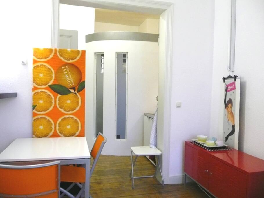 links essecke, rechts geschirr-schrank, rechts hinter der wand spüle, kühlschrank, 2 herdplatten, microwelle, die langen fenster gehören zum duschbad mit toilette