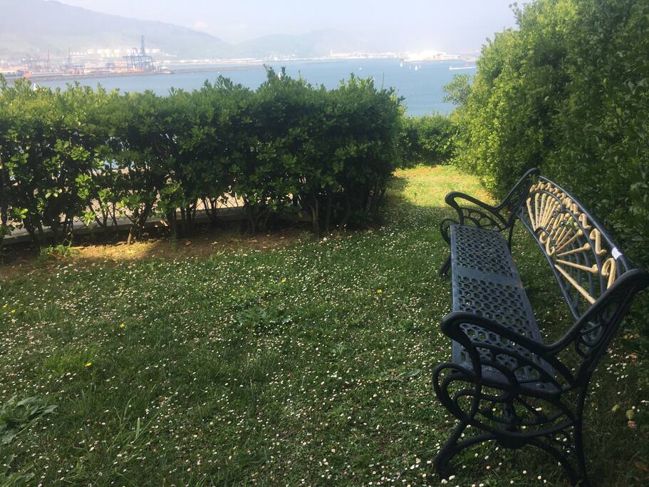 Jardín con vistas al mar con banco de hierro clásico.