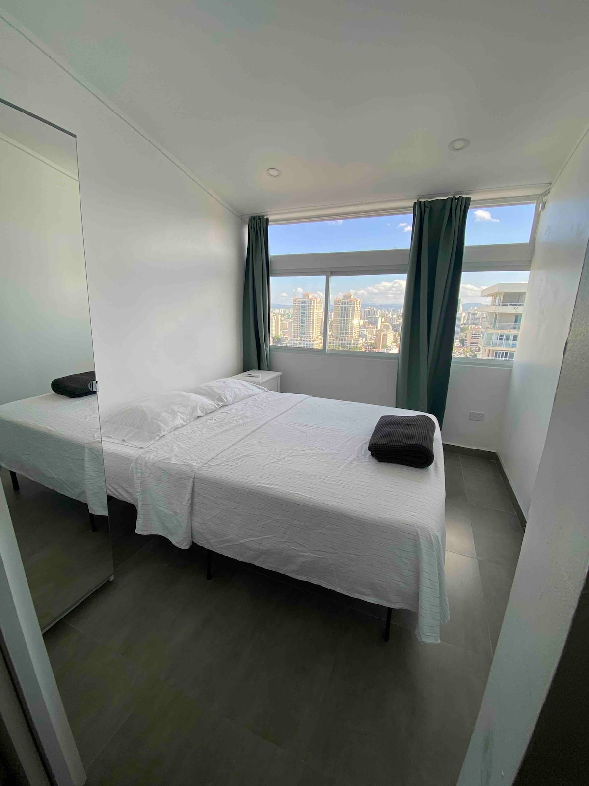 Queensize bed, met nieuw matras en matrastopper voor een comfortabelere nachtrust. Kledingkast om bagage op te bergen/kleding op te hangen met spiegel, nachtkastje en uitzicht op Penthouse City.