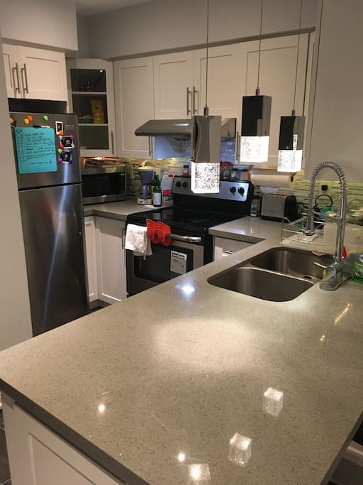 state of the art kitchen with brand new stainless steel appliances (stove+microwave+dishwasher+refrigerator+toaster+coffee maker) and kitchen utencils, cutlery and ample storage space
