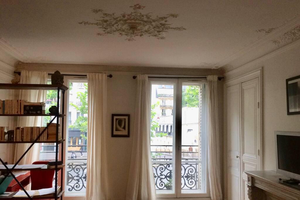 Living room with hardwood floors, marble fireplace and ornamental ceiling moulding.