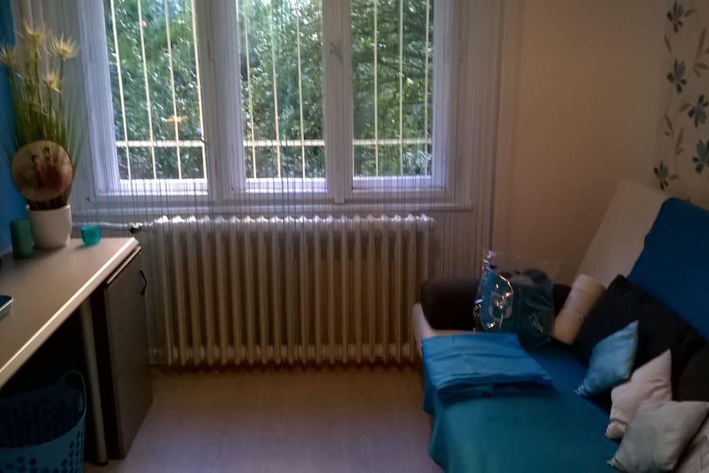 A hálószoba 1. türkiz színvilágú. Kinyitható, ágyneműtarrós IKEA Beddinge kanapé, vállfák, íróasztal, dossziék, irattartók, fölső szekrények a pakoláshoz. Laminált parkettás. Belső kertre néz, fekvése dél-keleti, beragyogja a nap kora délutánig.