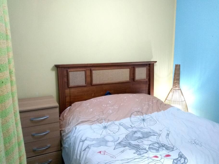 Cama matrimonial, cajonera y luz para ambiente acogedor.
