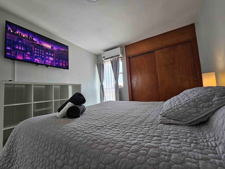 ห้องนอนใหญ่พร้อมเตียงควีนไซส์แยกขนาดเล็กระเบียงและสมาร์ททีวีขนาด 55 " 