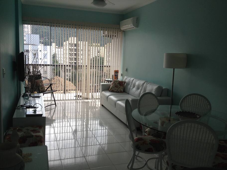 Sala com sofá de couro branco e ar condicionado, tipo split.