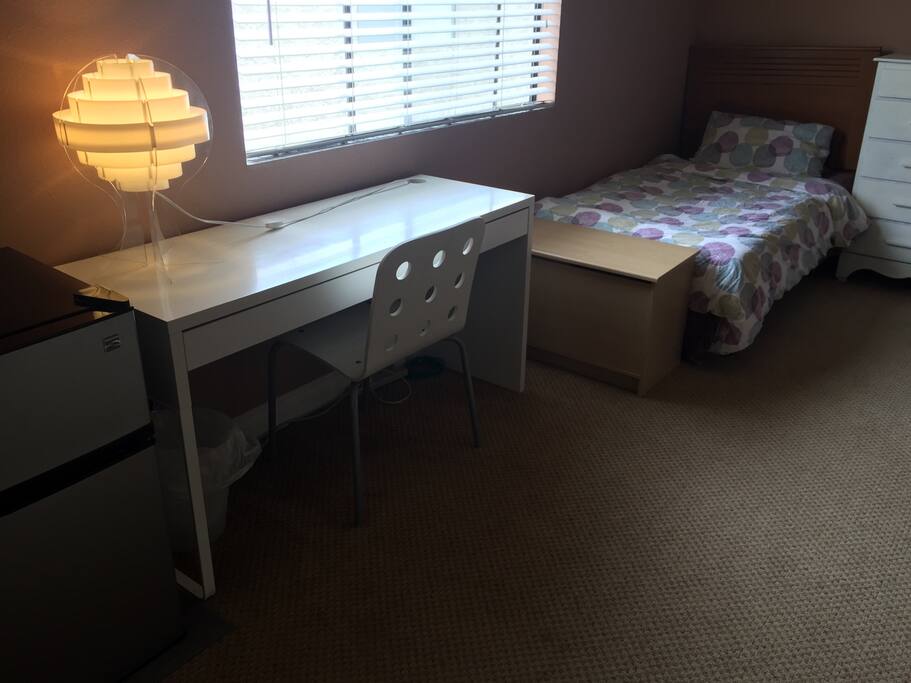 Desk and twin bed by window