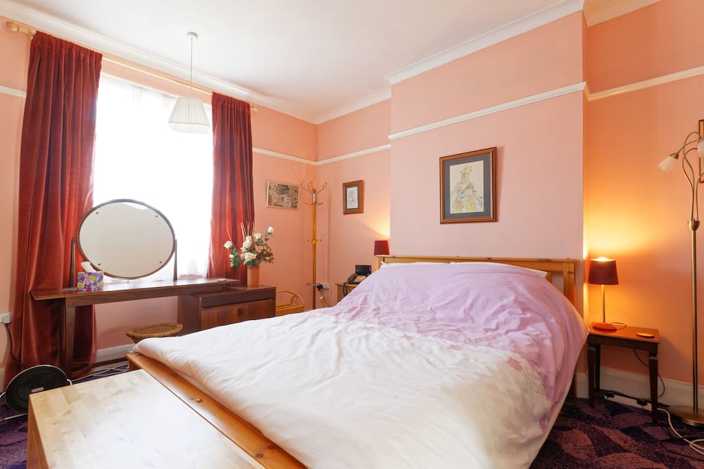 Delightful large bright bedroom available for reservations: fully furnished with dressing table, kingsize bed and duvet, trunk, 2 wardrobes with hangers, clothes rail, coat stand, lamps, bedside drawers, chest of drawers and your own iron and ironing board. Lots of provisions for you to unpack and put away your clothes and belongings.