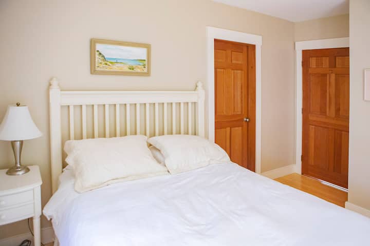 Beneden slaapkamer met queensize bed. Deuren verbinden met badkamer en woonkamer.