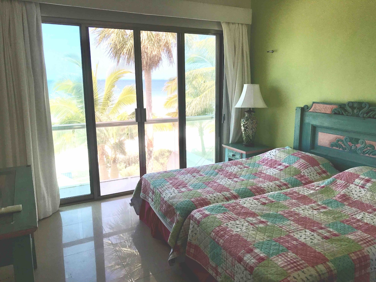 Spálňa s výhľadom na oceán, kde sú dve samostatné postele, klimatizácia, dve hojdacie siete a kúpeľňa s toaletou 