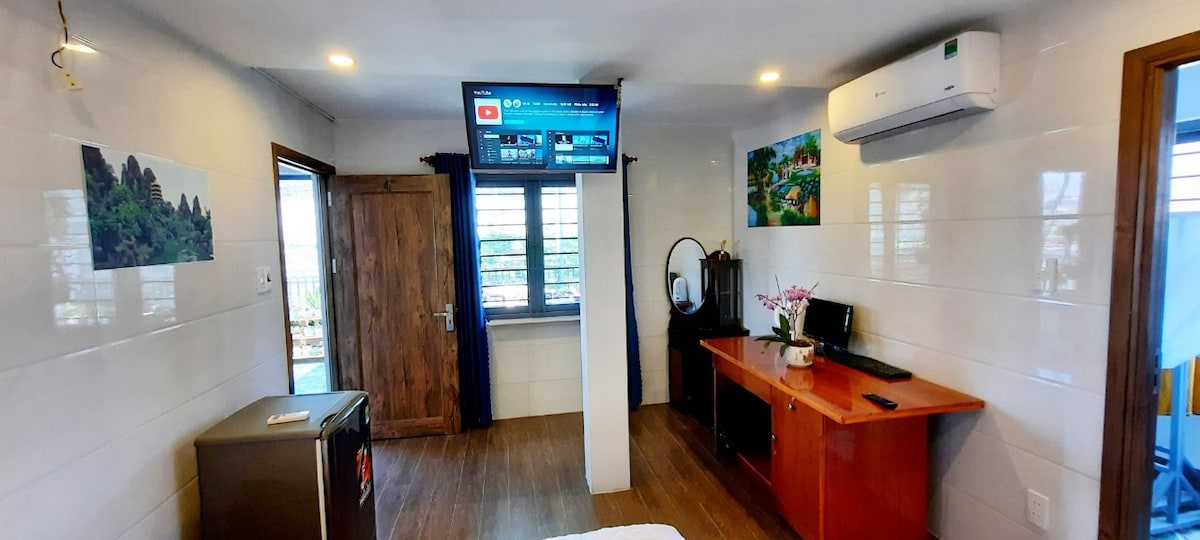 החדר עם  מיזוג אוויר, טלוויזיה עם מסך שטוח 40אינץ ', חדר רחצה פרטי, מקרר... והמרפסת מעל נהר דננג וגשר הדרקון