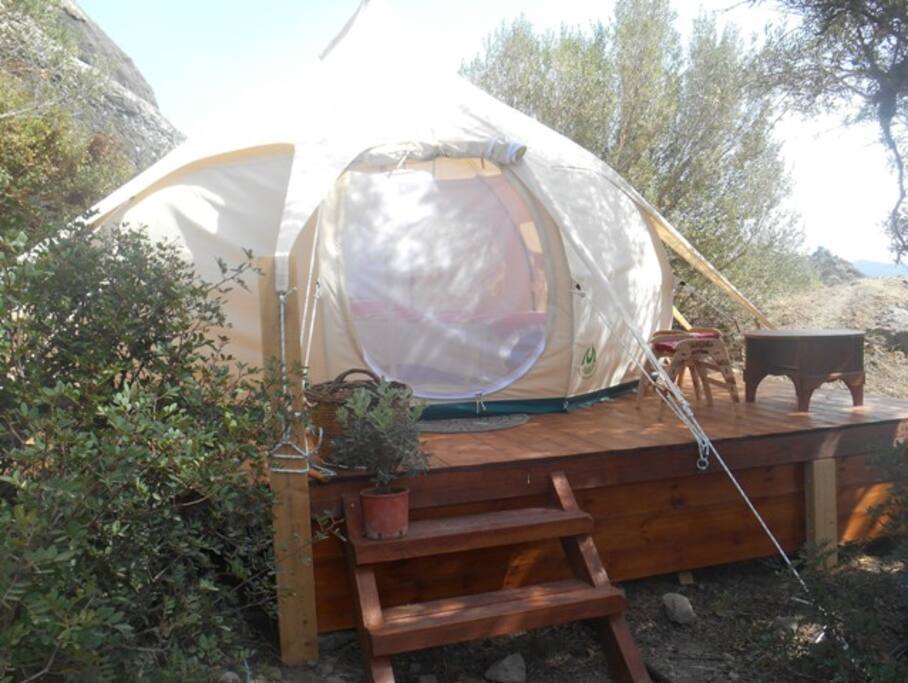 Tent is pitched on solid wooden platform with huge rocks in the background