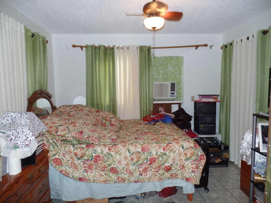 first room queen bed, with ac, with small ice box, with closet covered with curtain, with ceilinng fan