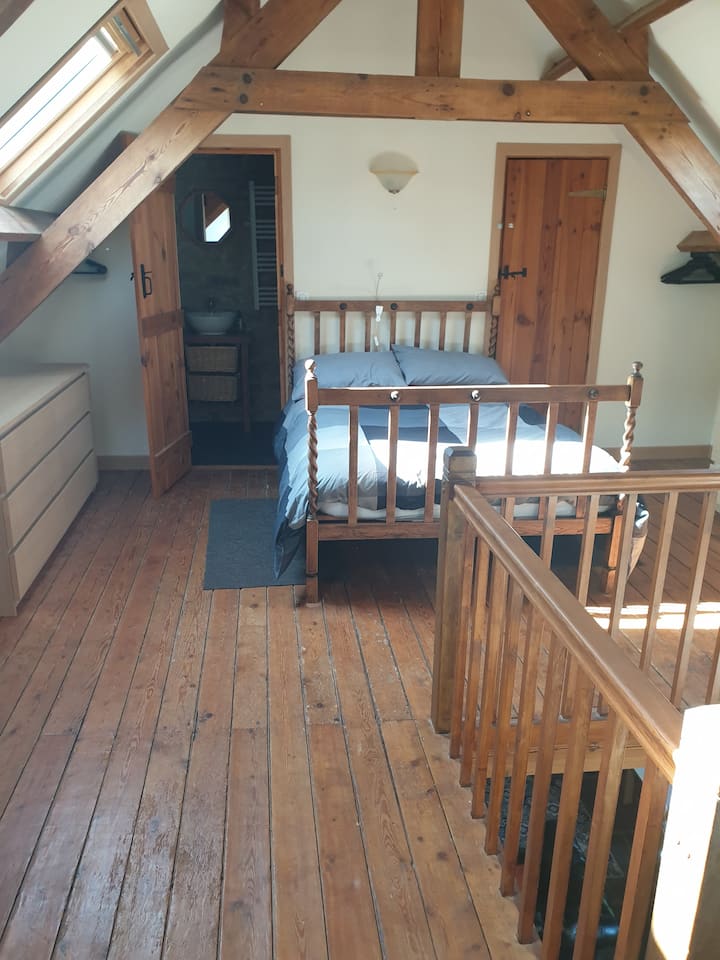 غرفة نوم في الطابق العلوي مع حمام داخلي وسرير مزدوج.