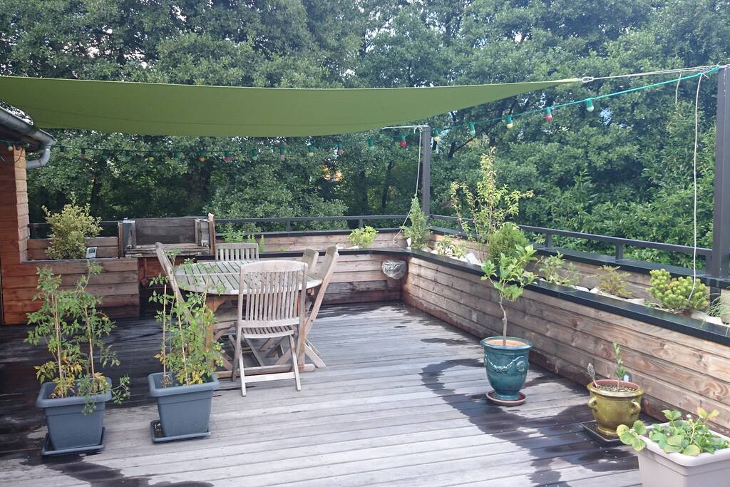 Vue de la terrasse l'été, avec une voile d'ombrage. Barbecue WEBER à votre disposition. Transats.