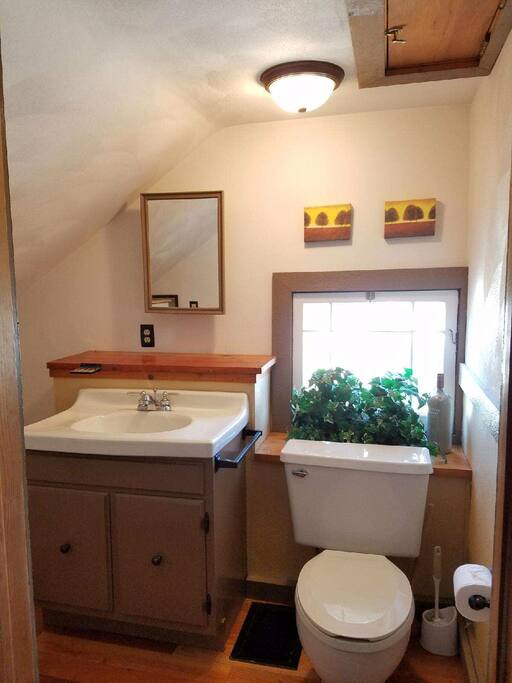 Private en suite half bath with new hardwood floors, large sink, toilet and plenty of shelves for storage (not pictured).