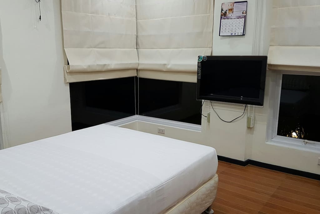 Inside the guestroom showing large windows with Roman curtains, 32" Led TV.