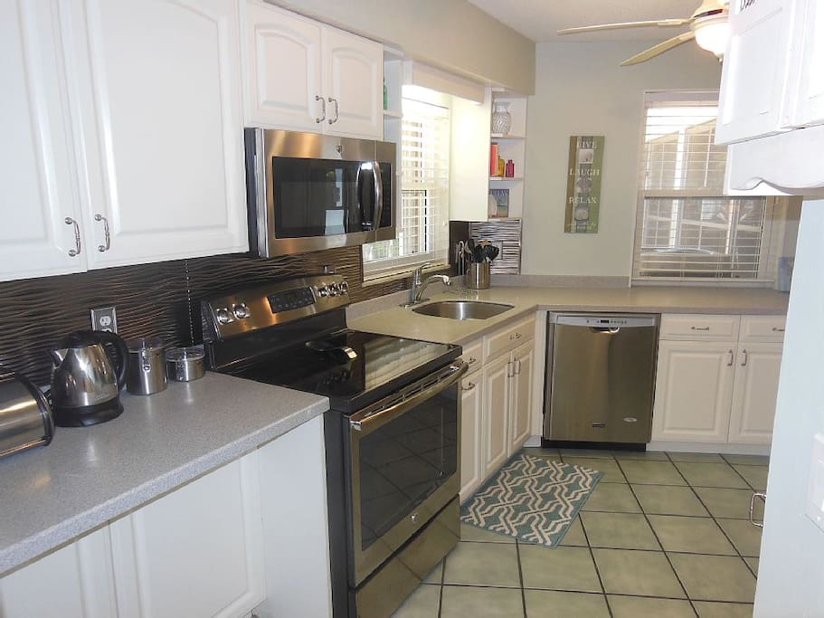 Well equipped kitchen with stainless steel appliances and Corian counters