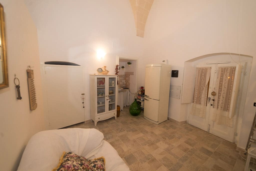 Living room con angolo cottura, divano e tavolo. Da qui si accede alla casa - entrata principale privata.