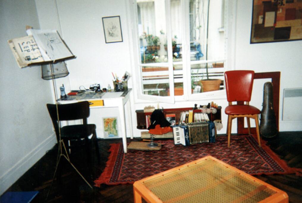 La grande pièce a une belle fenêtre fleurie et un piano