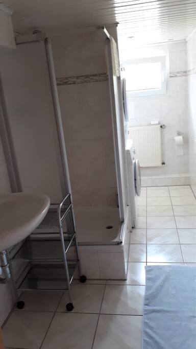 Badbereich mit Waschbecken, Dusche, Toilette, Waschmaschine und Trockner