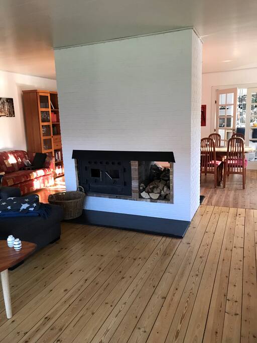 Stue opdelt i TV stue med stor sofa og brændeovn. Og ligeledes en spisestue med stort bord og 8 stole.