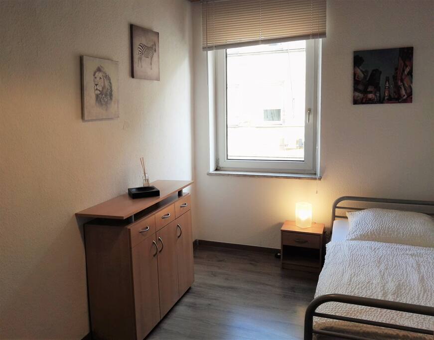 Es gibt eine Kommode und einen Nachttisch mit Lampe neben dem Bett.