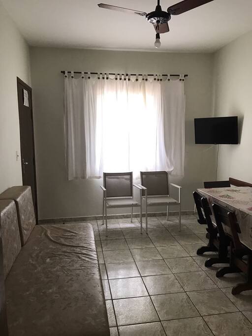 Sala com sofá cama, mesa de jantar e TV