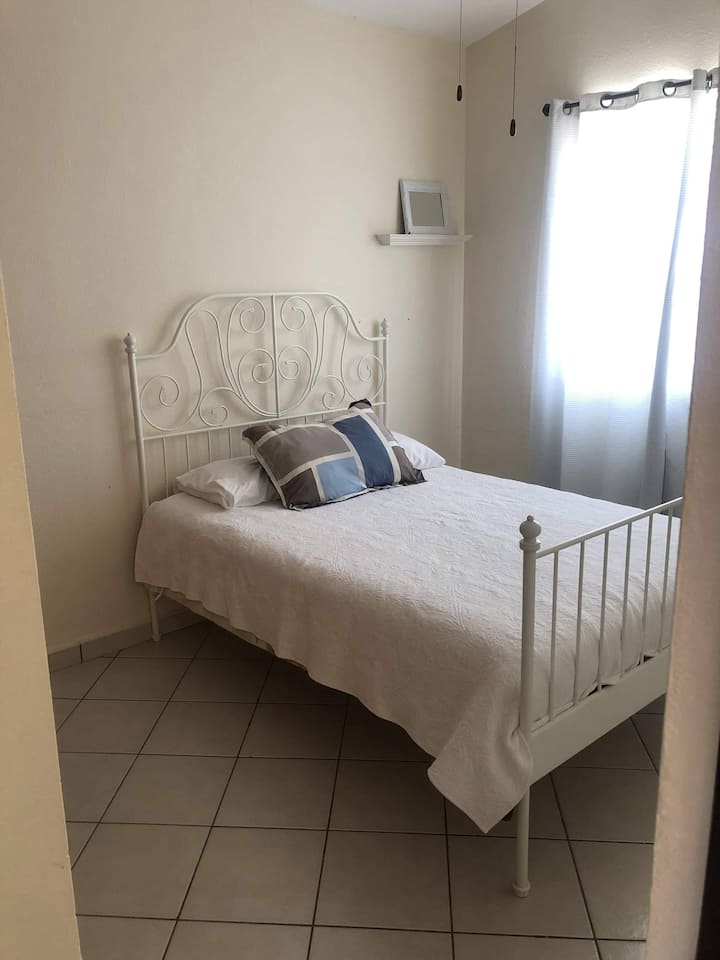 Spavaća soba s bračnim krevetom, prozorom i ormarom.