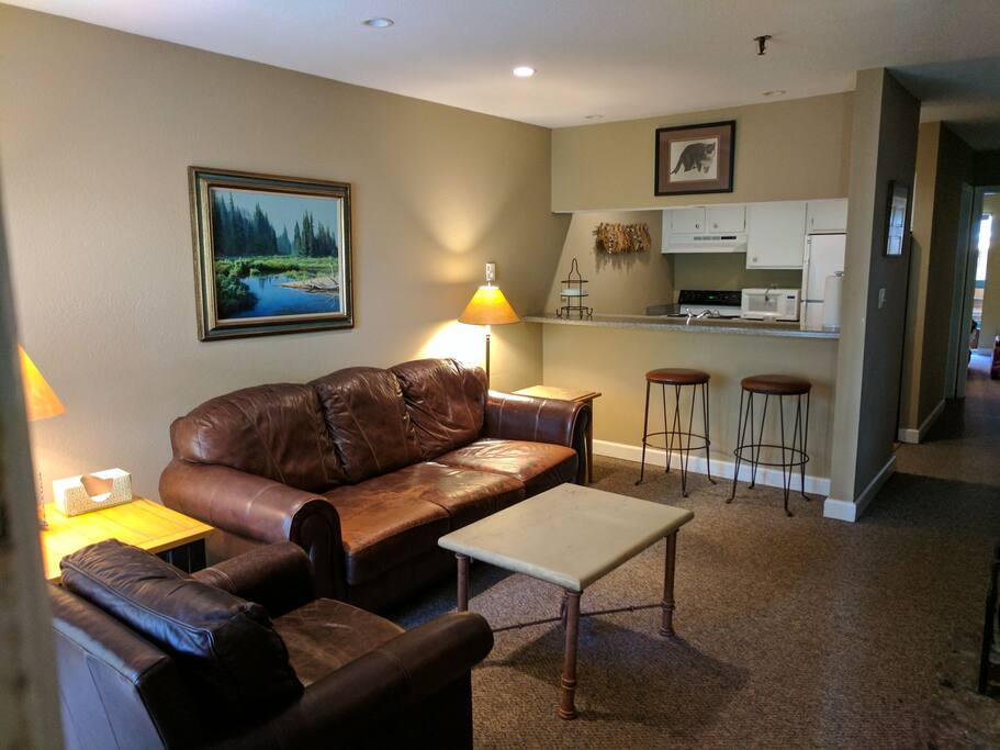 The living room has a leather couch and chair with a fire place.