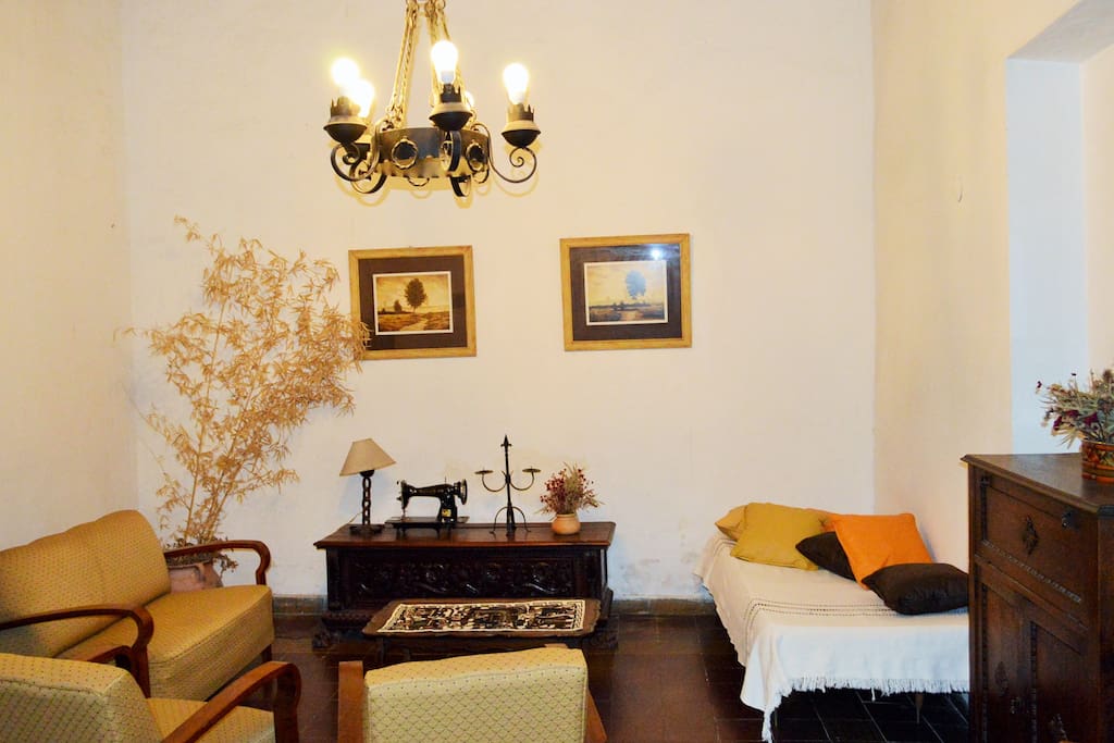 Amplia sala con tv cable, escritorio, sillones y sofá.