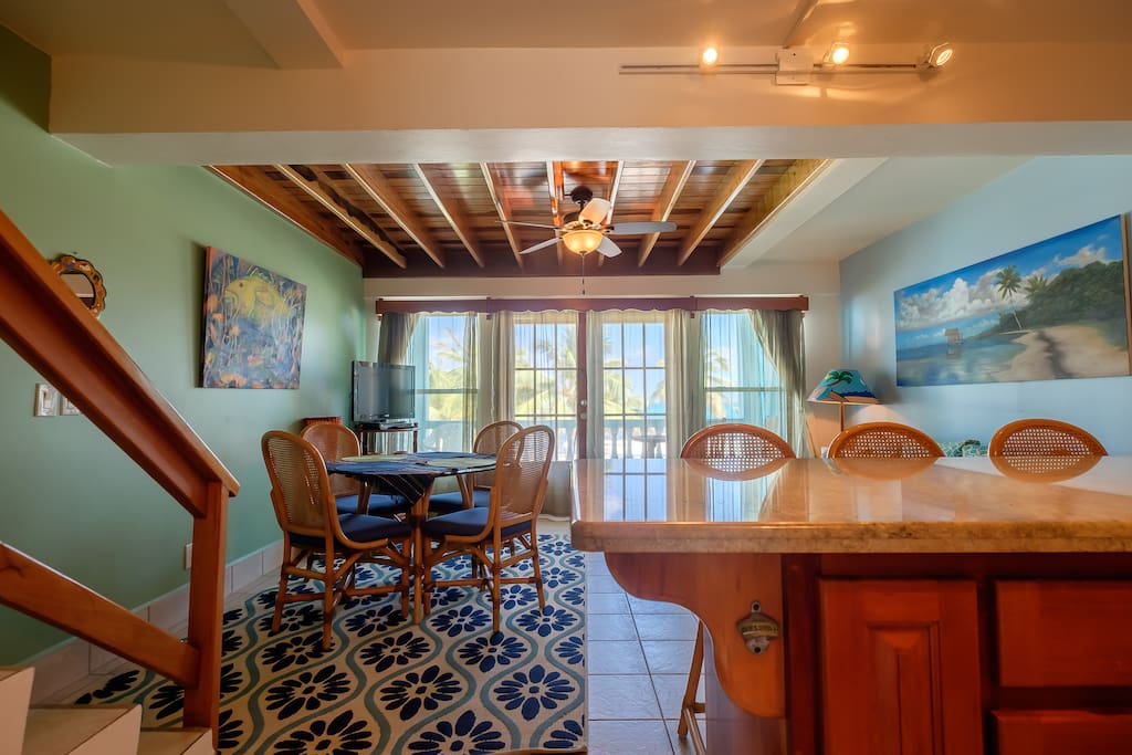 Long view of dining area from behind the kitchen counter. Stairs leading to loft area and master bedroom on the left.