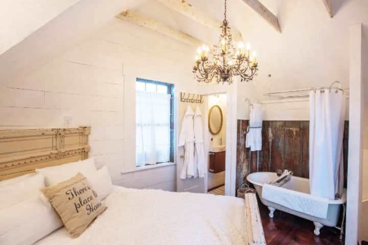 Our barndominum's bedroom upstairs offers a queen vintage bed, a clawfoot tub and shower combination open to the bedroom and a small private toilet room.  There is a towel-warmer on wall. Robes and slippers are provided!