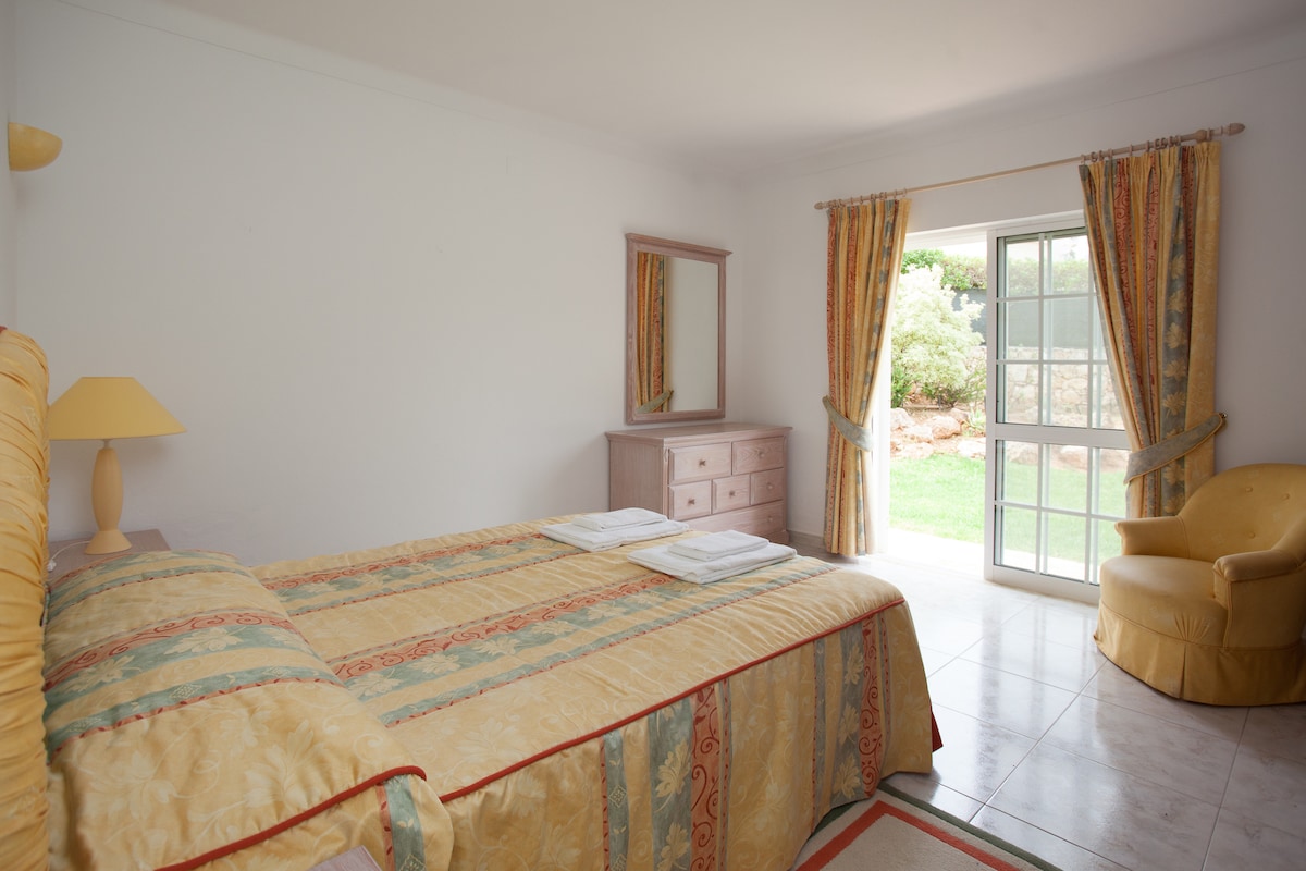 ห้องนอนใหญ่พร้อมห้องน้ำในตัว (ที่อาบน้ำฝักบัวเหนือห้องน้ำ) และประตูสู่สวน