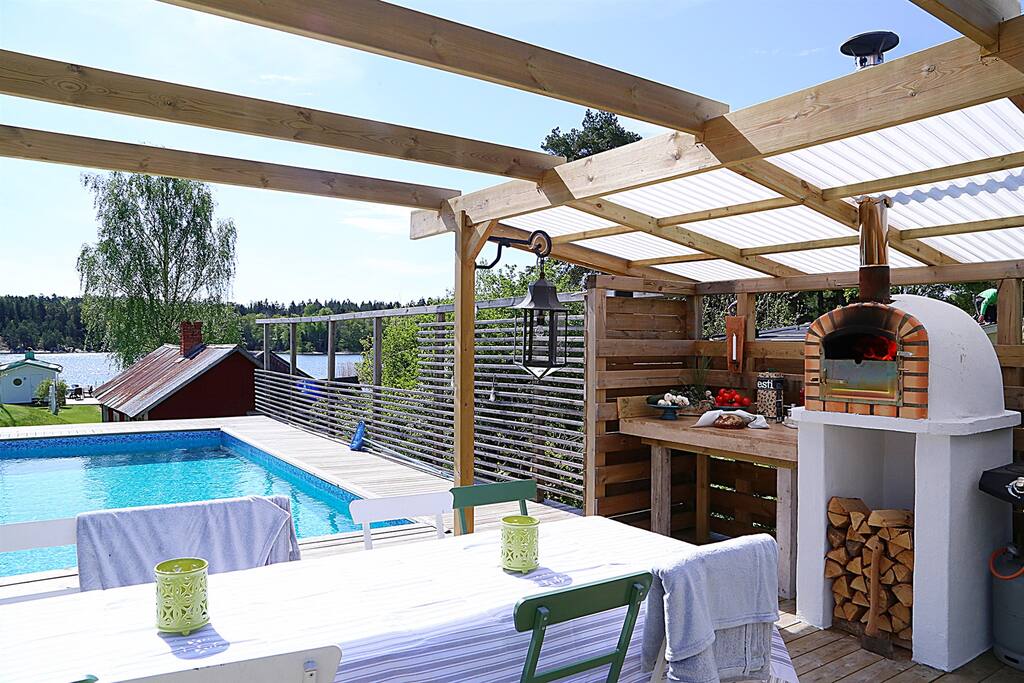 Pizzaugn och gasolgrill vid matplats under pergola vid poolen