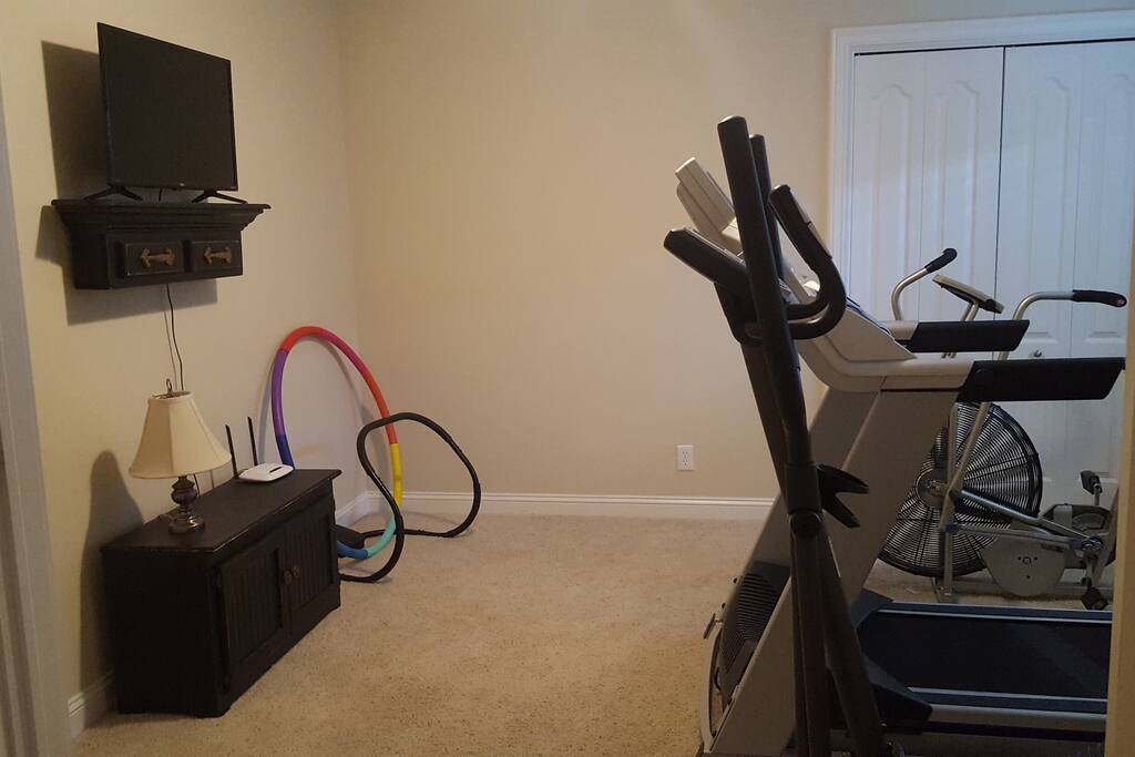 Exercise room with treadmill, bike, elliptical, free weights, and tv.